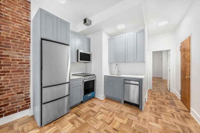 kitchen with light parquet flooring, appliances with stainless steel finishes, gray cabinets, and sink