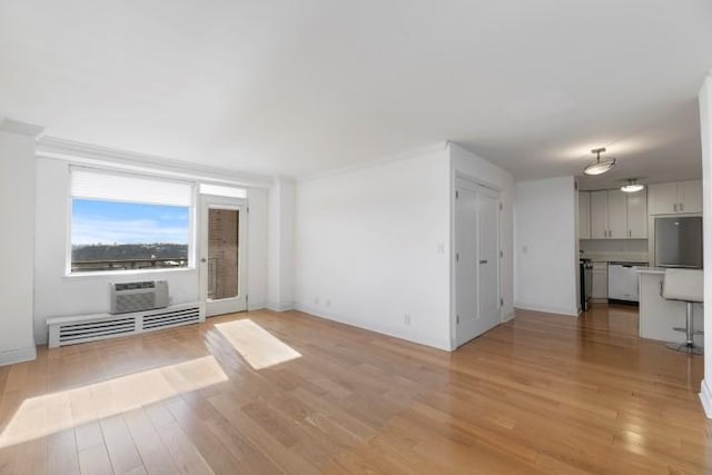 unfurnished living room featuring an AC wall unit and light wood finished floors