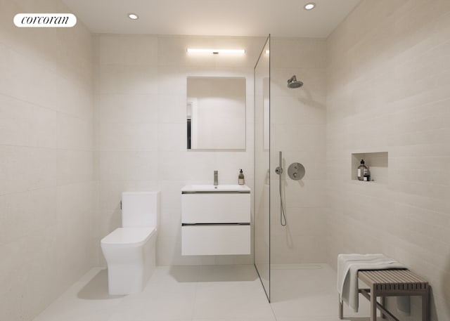 bathroom with a tile shower, tile walls, vanity, toilet, and tile patterned floors