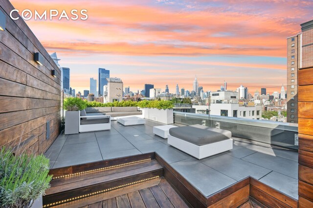 patio terrace at dusk with a grill, a wet bar, and area for grilling