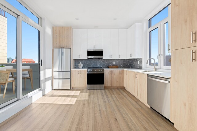 kitchen with sink, white cabinetry, light hardwood / wood-style flooring, light brown cabinets, and stainless steel appliances