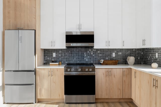 kitchen with stainless steel appliances, tasteful backsplash, light brown cabinets, and white cabinets