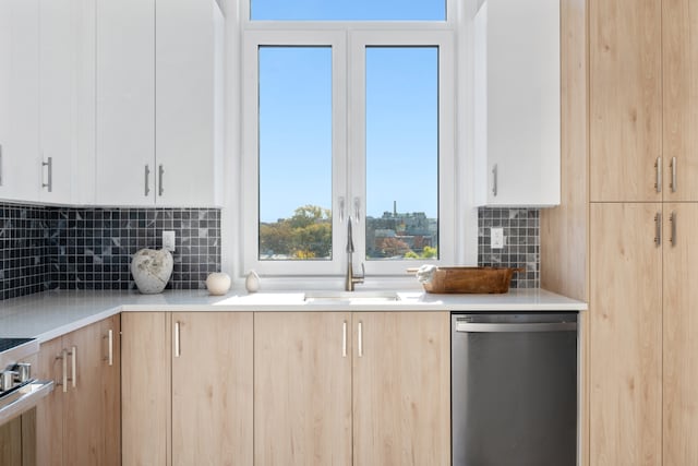 kitchen featuring white cabinetry, stainless steel dishwasher, sink, and backsplash