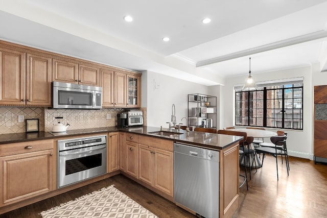 kitchen with dark wood-type flooring, sink, kitchen peninsula, and stainless steel appliances