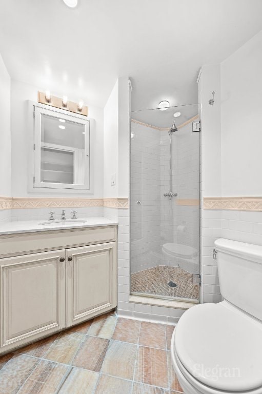 bathroom featuring walk in shower, tile walls, vanity, and toilet