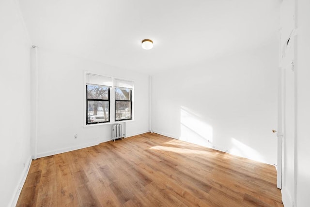 unfurnished room featuring radiator and hardwood / wood-style floors