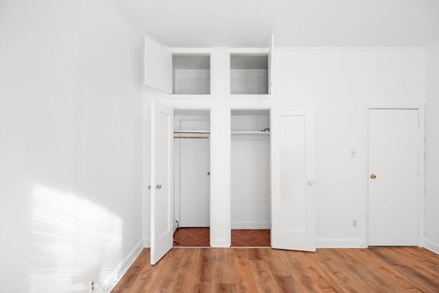 unfurnished bedroom with hardwood / wood-style floors and crown molding