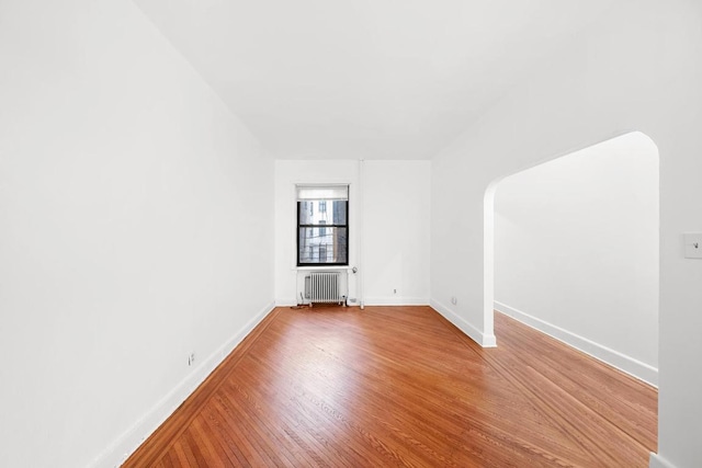 spare room with hardwood / wood-style flooring and radiator heating unit