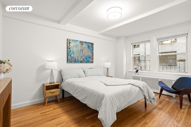 bedroom featuring radiator, hardwood / wood-style floors, and beamed ceiling