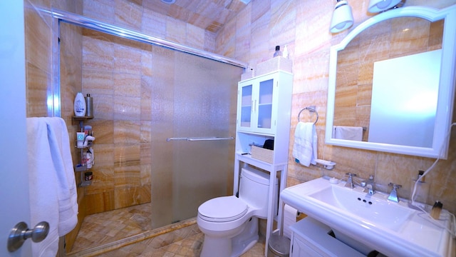 bathroom with a stall shower, toilet, tile walls, and a sink