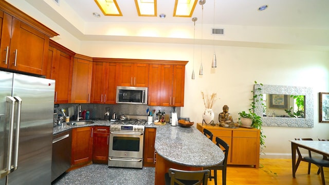 kitchen featuring a breakfast bar area, visible vents, a peninsula, decorative backsplash, and appliances with stainless steel finishes