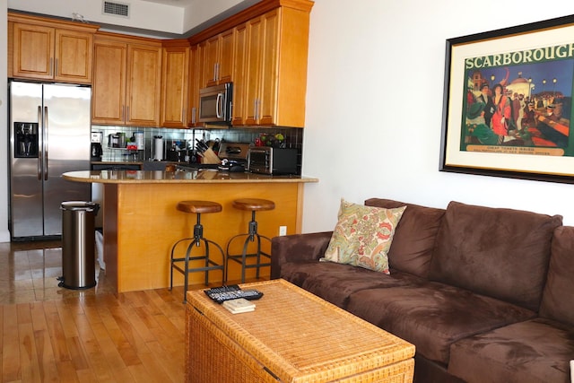 kitchen featuring stainless steel appliances, backsplash, visible vents, and wood finished floors