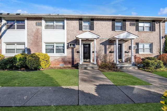 view of property with brick siding and a front yard