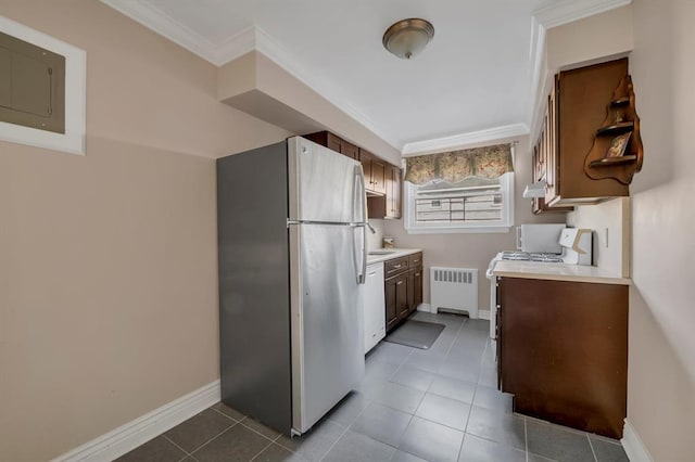 kitchen with tile patterned flooring, white appliances, light countertops, radiator, and crown molding