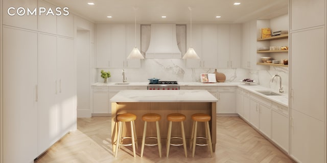 kitchen featuring decorative backsplash, custom range hood, a kitchen island, open shelves, and a sink