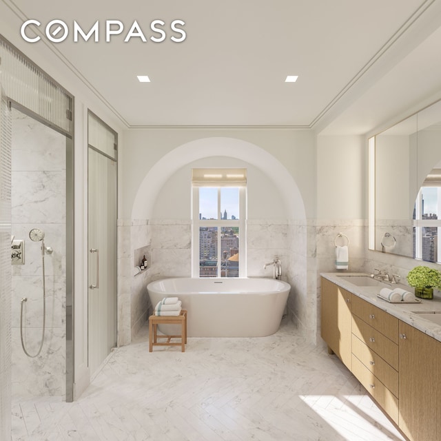 bathroom featuring a freestanding tub, a sink, tile walls, and double vanity