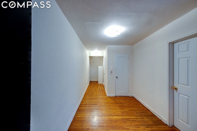 corridor featuring a textured ceiling and light hardwood / wood-style flooring