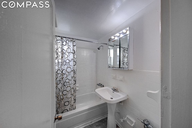 bathroom featuring tile walls and shower / bath combo with shower curtain