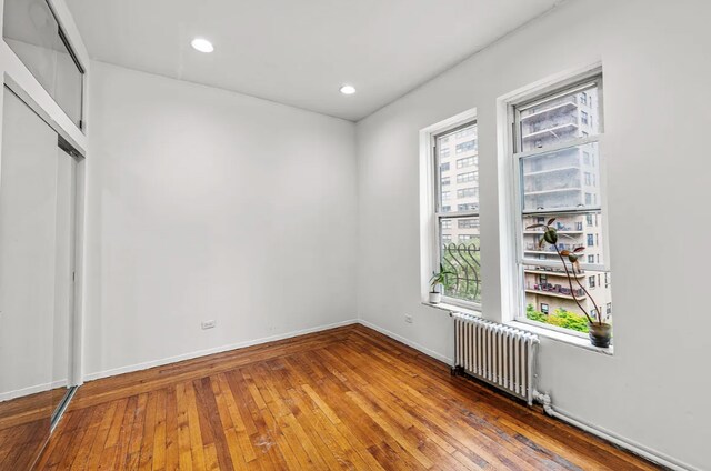 unfurnished room featuring wood-type flooring and radiator heating unit