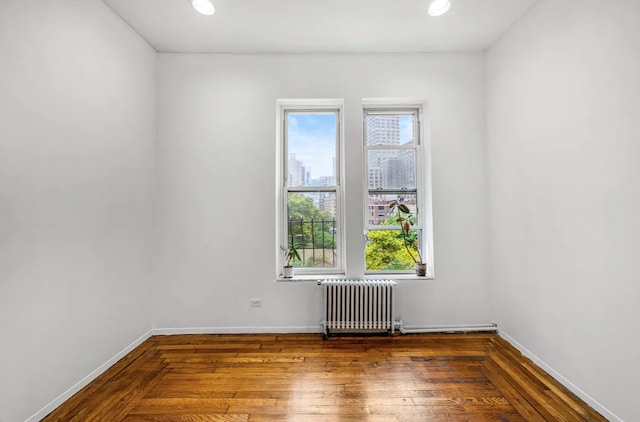 spare room featuring wood-type flooring and radiator heating unit