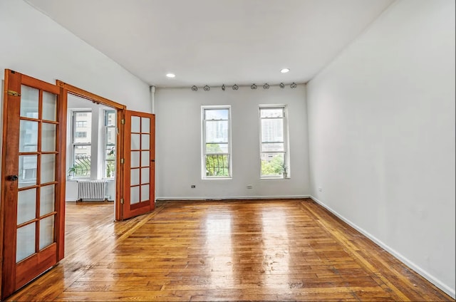 spare room with wood-type flooring, radiator heating unit, and french doors