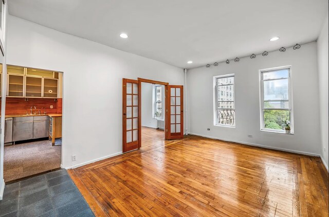 empty room featuring sink, wood-type flooring, and french doors