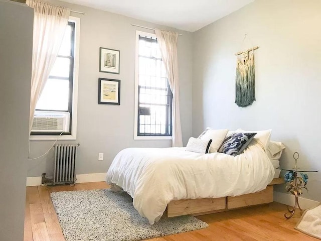 bedroom featuring cooling unit, hardwood / wood-style flooring, and radiator heating unit