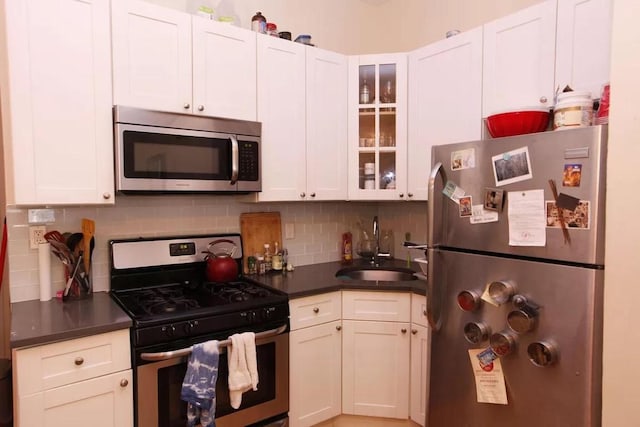 kitchen featuring appliances with stainless steel finishes, decorative backsplash, white cabinets, and sink