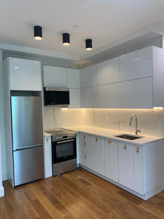 kitchen featuring dark wood-style flooring, stainless steel appliances, light countertops, white cabinetry, and a sink