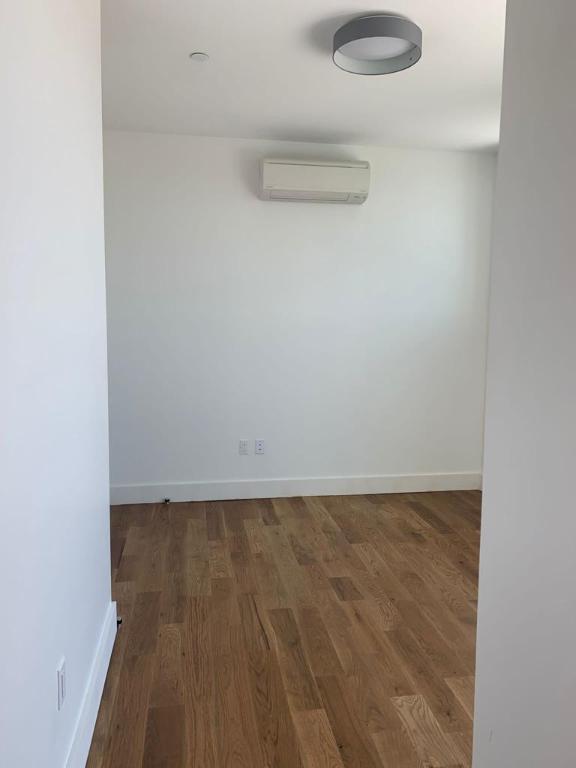 empty room featuring an AC wall unit, dark wood-type flooring, and baseboards