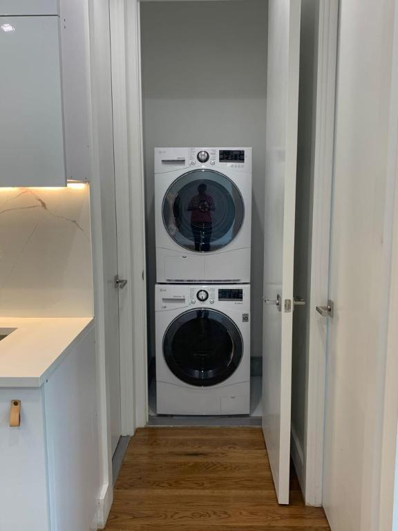 laundry area with dark wood-type flooring, stacked washer / dryer, and laundry area