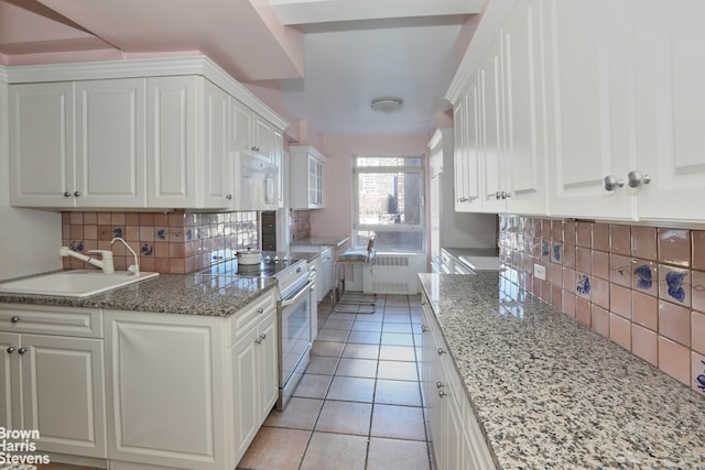 kitchen featuring decorative backsplash, white appliances, white cabinetry, a sink, and light tile patterned floors