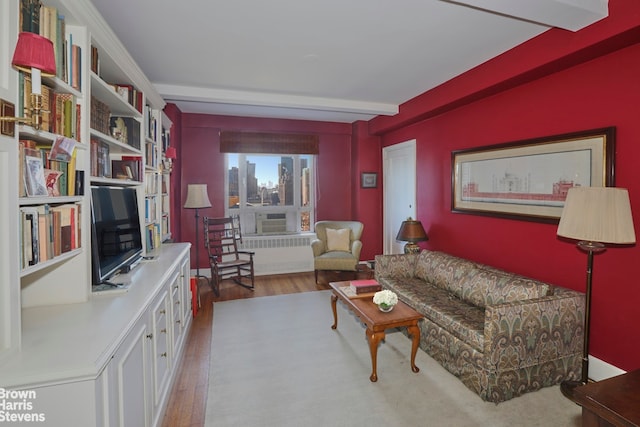 living area featuring beam ceiling, wood finished floors, and radiator