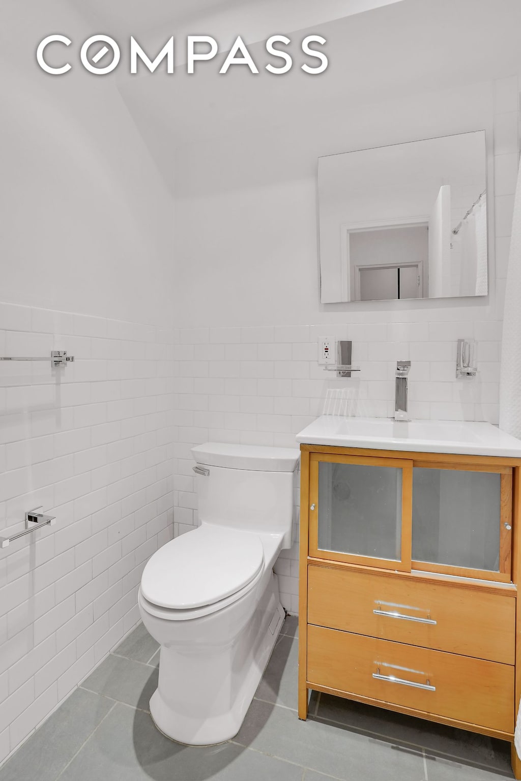 69 W 9th St Unit 8H, New York City, NY 10011 - bathroom featuring tile walls, vanity, tile patterned floors, and wainscoting