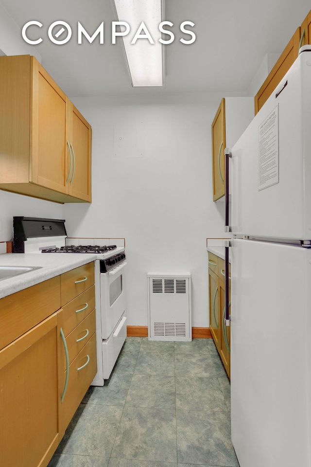 69 W 9th St Unit 8H, New York City, NY 10011 - kitchen with white appliances, light countertops, radiator heating unit, and baseboards