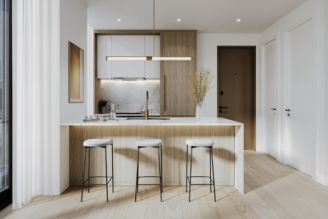 kitchen featuring a breakfast bar area, backsplash, white cabinets, and sink