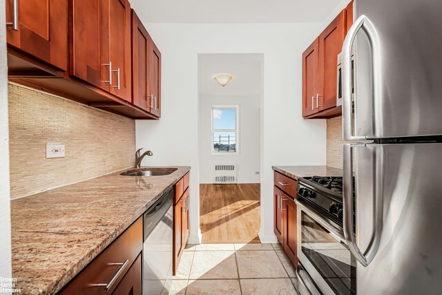 3050 Fairfield Ave Unit 8B, New York City, NY 10463 - kitchen with appliances with stainless steel finishes, radiator, a sink, light stone countertops, and decorative backsplash
