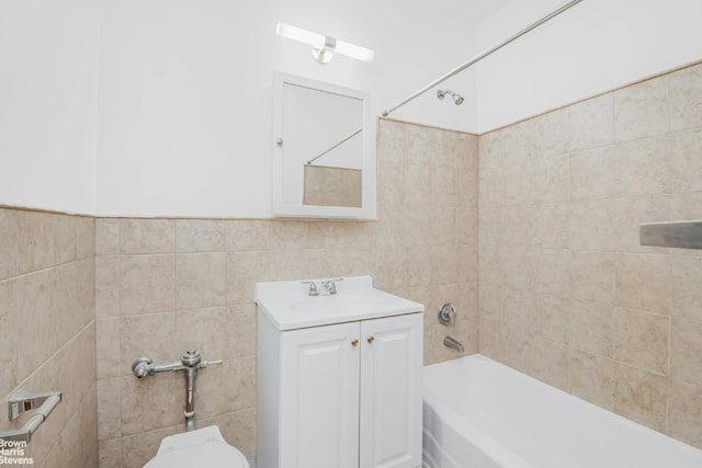 full bathroom with tiled shower / bath combo, vanity, tile walls, and toilet