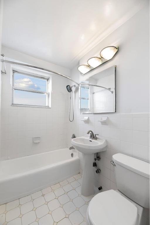 full bathroom featuring toilet, tile walls, tiled shower / bath, and sink