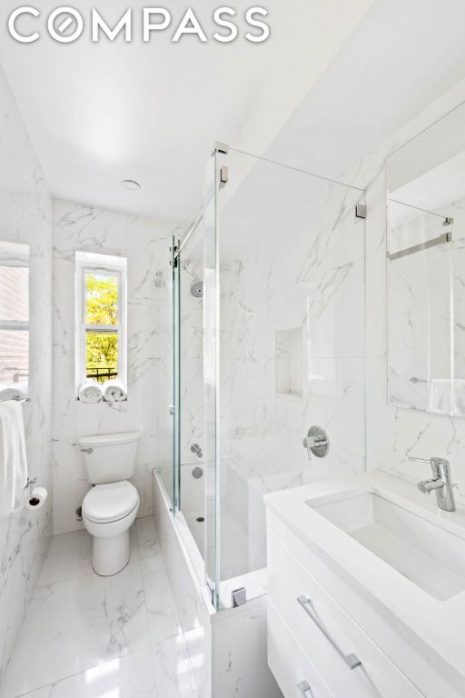 full bathroom featuring toilet, tile walls, vanity, and shower / bath combination with glass door