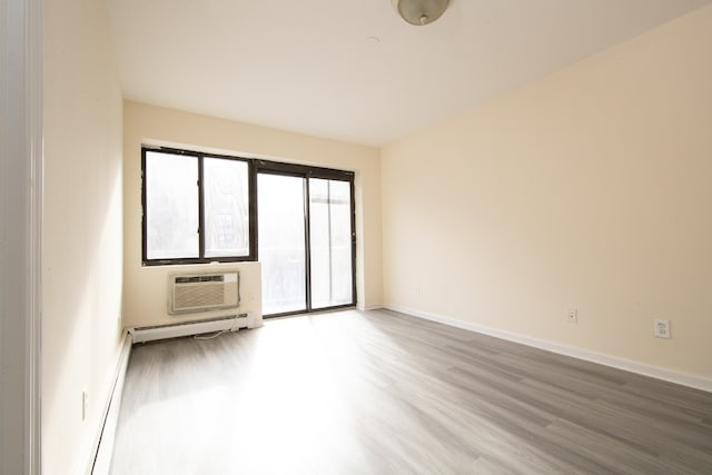 empty room with hardwood / wood-style flooring, baseboard heating, and a wall mounted air conditioner