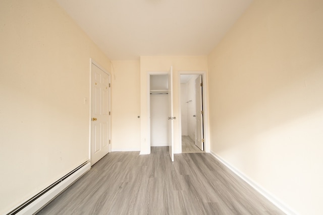 unfurnished bedroom featuring baseboard heating and light hardwood / wood-style flooring