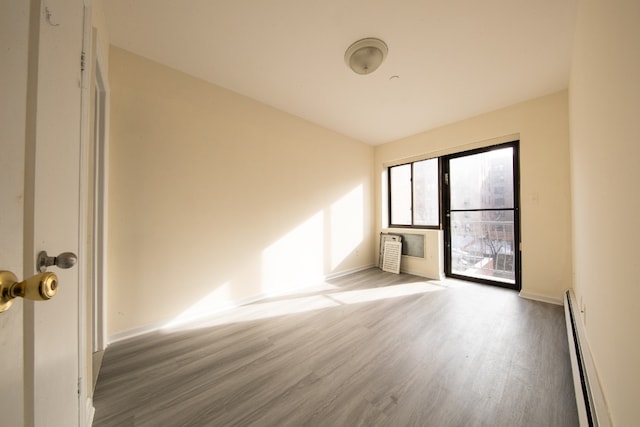 empty room featuring a baseboard heating unit and hardwood / wood-style flooring