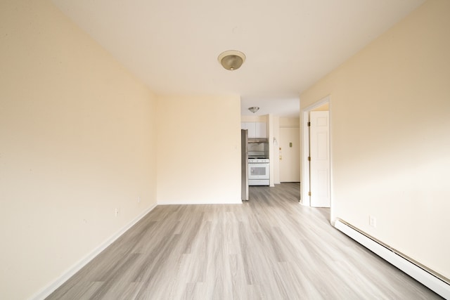 unfurnished room with a baseboard heating unit and light wood-type flooring