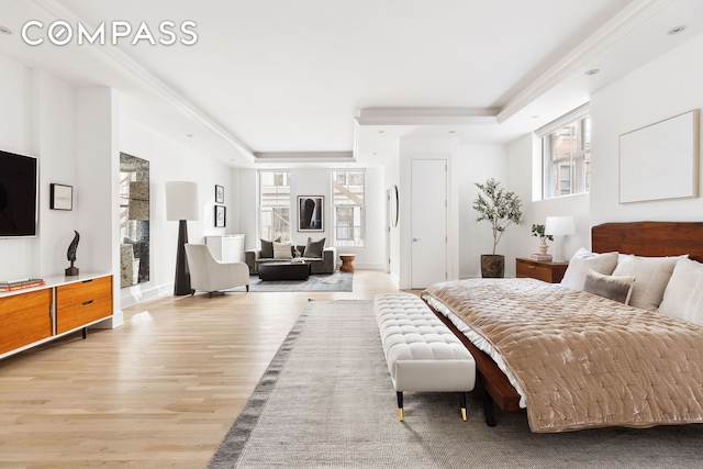 bedroom featuring multiple windows, light wood-type flooring, a raised ceiling, and crown molding