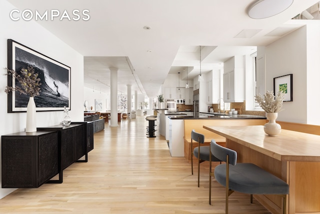 interior space featuring pendant lighting, a sink, light wood-style flooring, and a healthy amount of sunlight