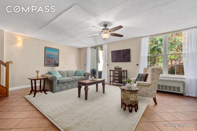 tiled living room with radiator heating unit and ceiling fan