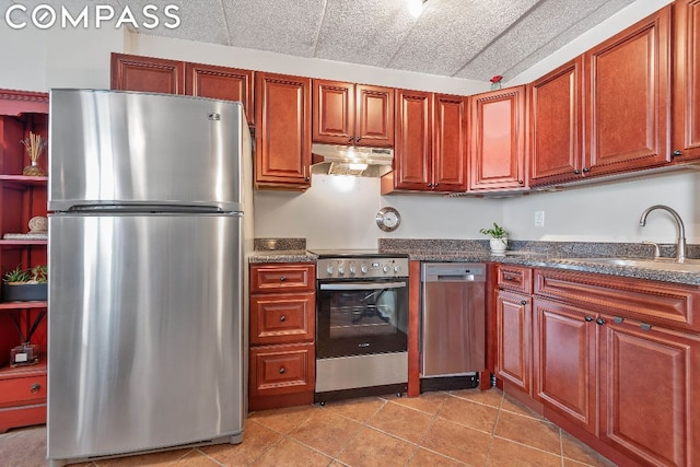 kitchen featuring under cabinet range hood, appliances with stainless steel finishes, light tile patterned flooring, and a sink