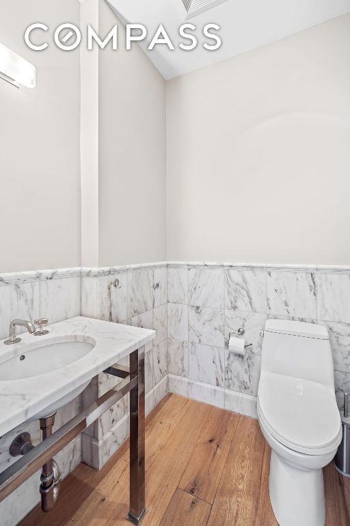 bathroom featuring hardwood / wood-style flooring, sink, tile walls, and toilet