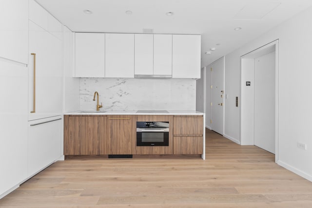 330 Grand St Unit 2A, New York City, NY 10002 - kitchen featuring oven, a sink, light countertops, light wood finished floors, and recessed lighting